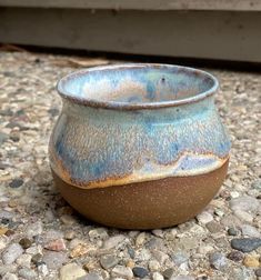 a blue and brown vase sitting on top of gravel