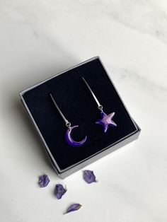 Stunning Moon and Star long dangle earrings. Special gift for many occasions. I take my inspiration from Scotland's nature, skies and seas and all things celestial. This design evokes deep calm and the mysticism of the sky at night. Each moon and star is individually hand painted with love and care. Once dry, I apply resin to protect the paint and to give a glassy effect.  Note that each painted moon and star is slightly different due to the application and setting of the paints; this adds to the uniqueness of the jewellery. The earring hooks and moon and star are all made of 925 sterling silver. The rubber back fasteners are hypoallergenic. The moon and star both measure 1.5 cm and the long earring hooks give a drop of 4.3cm when worn. The earrings come in a small grey gift box. A complem Painted Moon, The Sky At Night, Sky At Night, Long Earring, Purple Design, Moon And Star, Long Dangle Earrings, Silver Dangle Earrings, Sterling Silver Dangle Earrings