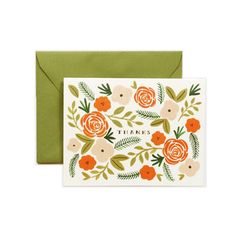 an orange and white card with flowers on it, sitting next to a green envelope