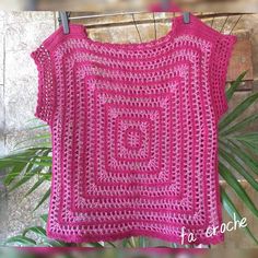 a pink crocheted top hanging on a clothes line next to a potted plant