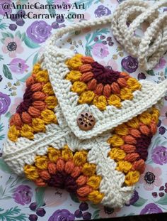 a crocheted purse sitting on top of a flowered table cloth with a white handle