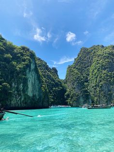 the water is crystal blue and clear with boats in it, surrounded by green mountains