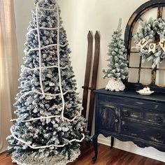 two decorated christmas trees sitting on top of a wooden floor next to a dresser and mirror