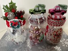 three glass jars filled with candy and ornaments on top of a doily covered table