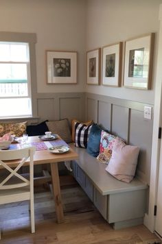 a room with a table, bench and pictures on the wall above it is shown