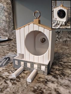 a white birdhouse with a hole in the roof and a camera attached to it