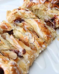 some kind of pastry with nuts on it sitting on a white plate and drizzled with icing