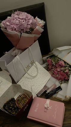 pink flowers are sitting on top of the table next to some books and other items