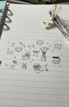 a notepad with drawings on it next to a pen and some other things in the background