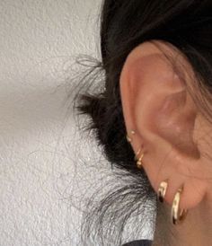 a close up of a person's ear with two small gold hoop earrings on it