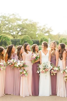 a group of women standing next to each other wearing dresses and holding bouquets in their hands