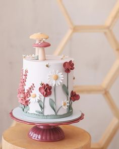 a white cake with flowers and a mushroom on top