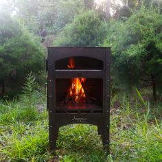 an outdoor wood stove in the middle of a field with grass and trees around it