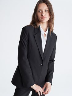 A tailored piece with a structured silhouette, this blazer is wrinkle-resistant and crafted with 4-way stretch for ease of movement. Detailed with crisp notch lapels and made with a single button closure. Finished with seaming details along the sleeves and back.  Material: 66% Polyester, 31% Viscose, 3% Elastane. Professional Wear, Calvin Klein, Blazer