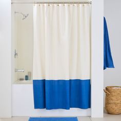 a white and blue shower curtain next to a bath tub with a towel on it