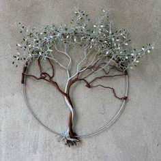 a metal tree with white flowers on it's branches and roots in the shape of a circle