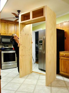 a woman standing in the doorway of a kitchen with an open door to another room