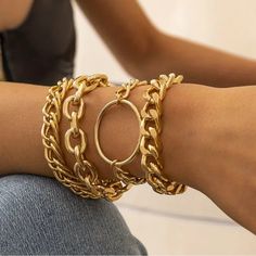 a close up of a person wearing gold bracelets and rings on their arm,