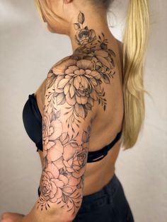 a woman with a flower tattoo on her back shoulder and arm is looking at the camera