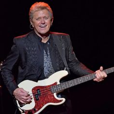 an older man is playing the guitar on stage