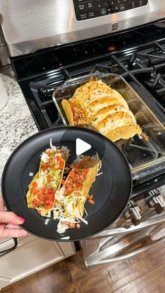 a person holding a plate with food on it in front of an open stove top oven