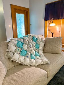 a couch with a blanket on it in front of a window and door to another room