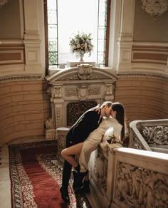 a bride and groom kissing in front of a fireplace