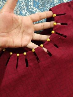 a person's hand with gold beads on it and a red dress in the background