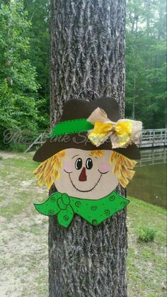 a tree with a paper cutout of a scarecrow wearing a hat and green scarf