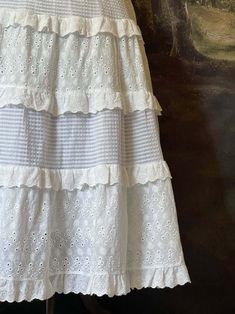 This historically inspired maxi skirt is the perfect base to build all of your historical looks upon. Crafted in dainty floral embroidered cotton, & adorned with layers of delicate lace trim; the tiered silhouette & stretchy waistband of this skirt are perfect for accommodating a day of frolicking in the field outside your cottage! Sizing: ✧IN✧ Waist Hips Length S/M 25-38 Inches Up to 56 Inches 32 Inches L/XL 30-42 Inches Up to 60 Inches 32 Inches ✧CM✧ Waist Hips Length S/M 62.5-95 CM Up to 140 CM 80 CM L/XL 75-105 CM Up to 150 CM 80 CM Materials:Outer - 70% Cotton, 30% Polyester. Lining - 100% Cotton. Care:Machine wash on gentle cycle with like colors. Tumble or air dry. Please be aware that this item was photographed using a petticoat or similar undergarments. Cottage Skirt, Summer Tiered Maxi Skirt With Lace Patchwork, Tiered Maxi Skirt With Lace Patchwork For Summer, Lace Tiered Maxi Skirt With Ruffles, Lace Maxi Skirt With Ruffles And Tiered Design, Flowy Tiered Skirt Dress With Lace Trim, Spring Tiered Maxi Skirt With Lace Trim, White Bohemian Tiered Maxi Skirt, Spring Lace Trim Tiered Maxi Skirt