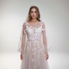 a woman wearing a wedding dress with long sleeves and a veil on her head, standing in front of a white background