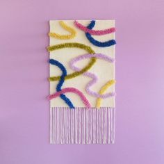 a colorful wall hanging on the side of a purple wall