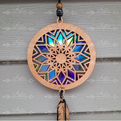 a wooden dream catcher hanging on the side of a building with an iridescent window