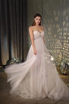 a woman in a white dress standing next to a mirror ball and wearing a long veil