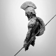 a statue made out of paper on top of a wooden pole with a wire attached to it