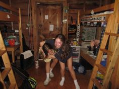 two young women standing on the floor in a room with bunk beds and other items