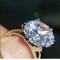 a close up of a person holding a ring with an oval shaped diamond in it