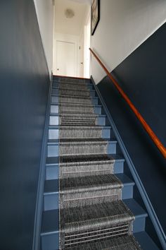 a set of stairs leading up to a hallway with blue walls and carpeted steps