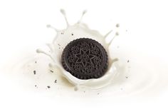 an oreo cookie with milk splashing around it