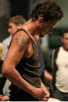 a man with a tattoo on his arm is preparing food in a kitchen while others look on