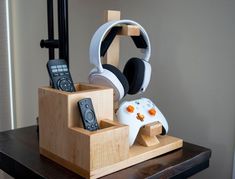 a wooden stand with two remotes and headphones on it, one is in the shape of a video game controller