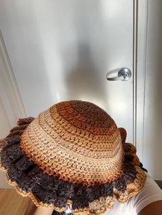 a woman wearing a brown and tan crocheted hat