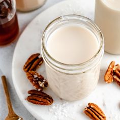 there is a glass of milk and some pecans on the plate