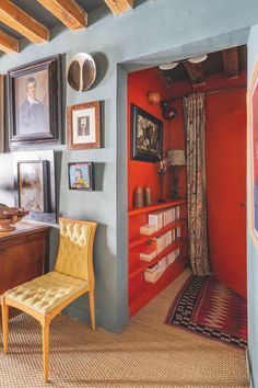 a room with blue walls and pictures on the wall, including a chair in front of a bookshelf