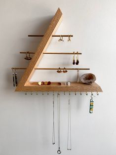 a wooden shelf with several pairs of earrings hanging from it's sides and hooks attached to the wall