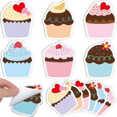 a hand is holding a sticker with cupcakes on it and hearts in the middle