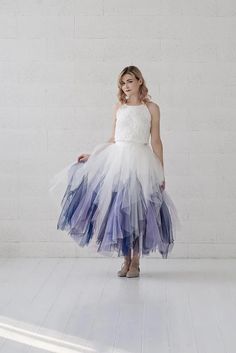 a woman in a white and blue dress is standing on the floor with her hands behind her back