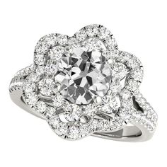 a white gold ring with an intricate flower design and round brilliant cut diamonds in the center