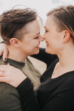 two women embracing each other and smiling at each other's side with their heads close to one another