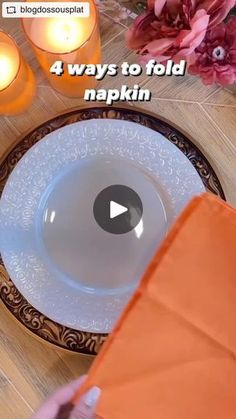 a person holding an orange napkin over a white plate on top of a wooden table